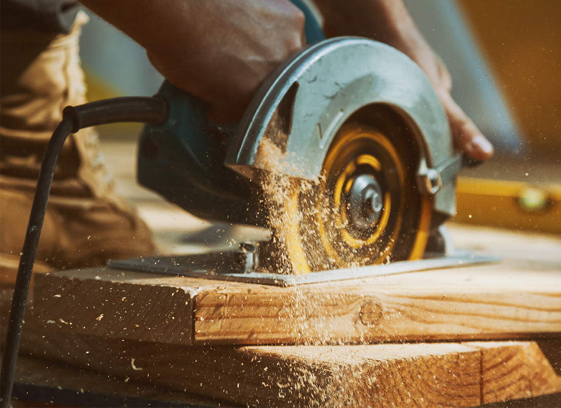 Contractor Insurance & Bonds - Close Up Shot of Carpenter Using Saw to Cut Wood on Job Site